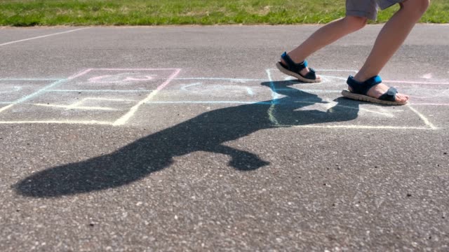 Boy-jumps-playing-hopscotch-in-the-street.-Close-up-legs.-Side-view.