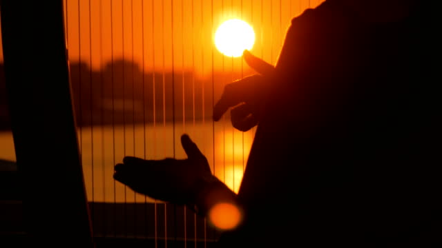 Frauen-Silhouette-spielt-Harfe-bei-Sonnenuntergang