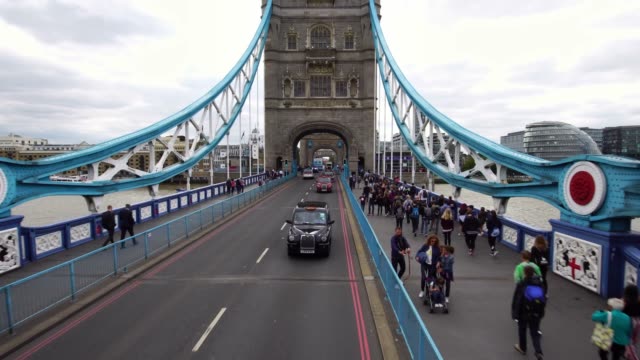 Drone-shot-of-a-black-taxi-cab-driving-on-the-iconic-Tower-Bridge-in-London,-Great-Britain