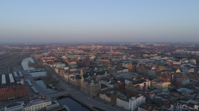View-of-Malmö-city-at-dusk.-Aerial-drone-shot-flying-over-cityscape-skyline-at-sunset,-Sweden
