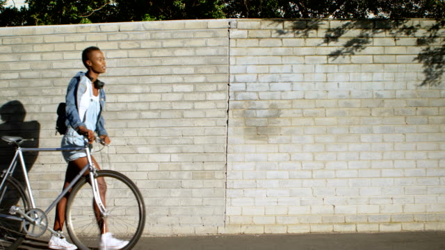 Mujer-caminando-con-la-bicicleta-en-la-ciudad-de-calle-4k