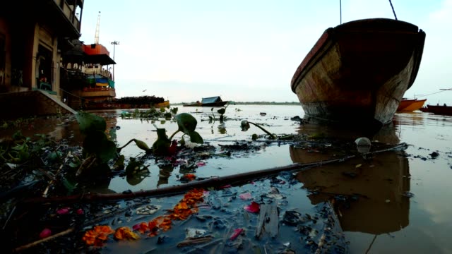 Hochwasser-auf-Manikarnika-Ghat-Einäscherungsort-Varanasi-schwarze-Kohlen-Zweige-schwimmen-in-Flussboot-auf-Pier-weit-Rinde-mit-Brennholz-und-Gaskrematorien