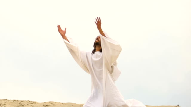 Muslim-falls-to-knees-in-desert,-raising-hands-praying-Allah-for-forgiveness