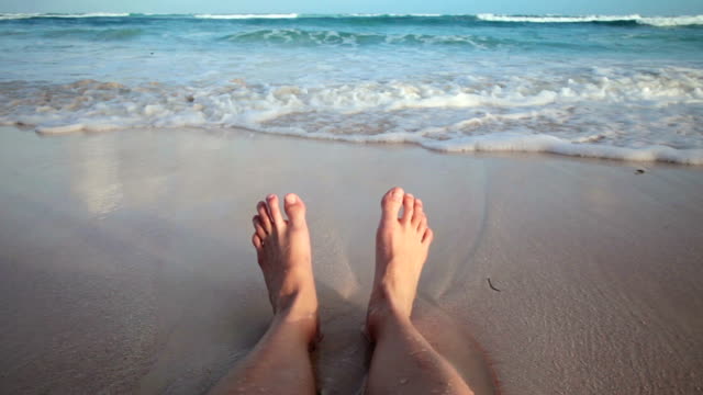 Mädchen-sitzt-am-Strand-und-lassen-Sie-Ihre-Füße-nass
