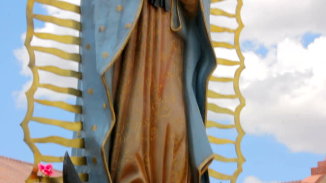 Inclinación-para-revelar-una-estatua-de-la-Virgen-Guadalupe-y-una-iglesia-de-Adobe
