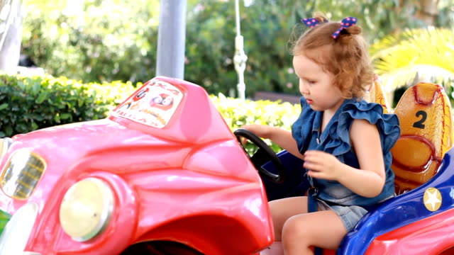 Muchacha-del-niño-y-monta-un-automóvil-eléctrico-en-el-parque-para-el-entretenimiento.