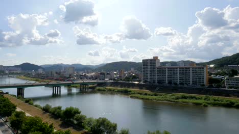 The-view-of-the-city-from-the-rooftop,-the-river-flowing-between-the-bridges,-the-sky-with-clouds-and-the-green-mountains,-the-apartment