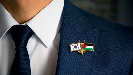 Businessman-Walking-Towards-Camera-With-Friend-Country-Flags-Pin-South-Korea---Palestine