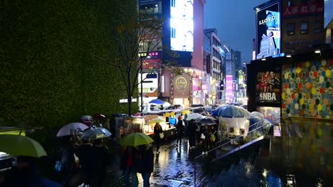 Myeong-dong-Market.People-walking-with-umbrellas-on-a-rainy-day-at-shopping-street-at-night,-Seoul,-South-Korea