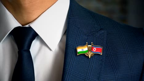 Businessman-Walking-Towards-Camera-With-Friend-Country-Flags-Pin-India---North-Korea