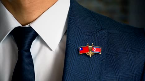 Geschäftsmann-zu-Fuß-in-Richtung-Kamera-mit-Freund-Land-Flaggen-Pin-Taiwan---Nordkorea