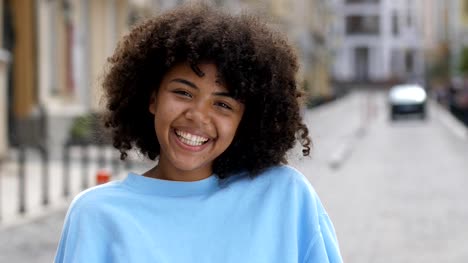 Outdoor-portrait-of-laughing-curly-mixed-race-girl