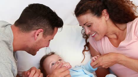 Baby-boy-being-tickled-by-parents-on-bed