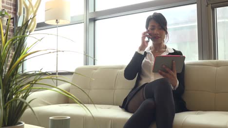 Telefonkonversation-mit-wunderschöner-asiatischer-Frau,-die-Ipad-zu-Hause-nutzt