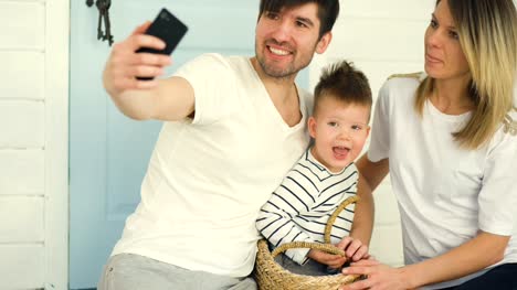 Padre-de-la-familia-feliz-hacer-selfie-con-su-esposa-y-su-hijo-pequeño-en-frente-de-su-puerta-de-casa