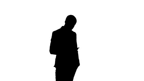 Silhouette-Young-man-in-suit-walking-and-sending-text-message-on-mobile-phone