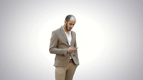 Junger-Mann-im-Anzug-zu-Fuß-und-senden-Textnachricht-auf-Handy-auf-weißem-Hintergrund