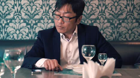 Hombre-asiático-en-traje-de-empresario-esperando-en-el-café-su-comida.-Largas-esperas-para-pedir.-Nervioso