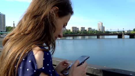Schöne-Frau-mit-einem-Smartphone-in-der-Nähe-des-Flusses