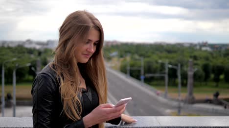 Fröhliche-junge-Frau-Blondine-nutzt-eine-Smartphone.