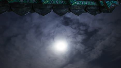 Rollo-de-noche-del-alero-del-templo-con-la-luna-y-las-nubes-en-movimiento