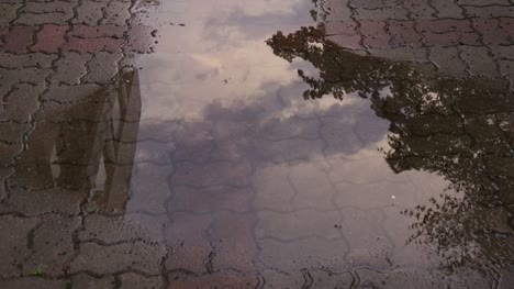 Vista-de-timelapse-del-cielo-reflecte-sobre-el-agua-en-bloque-de-la-acera-después-de-la-lluvia