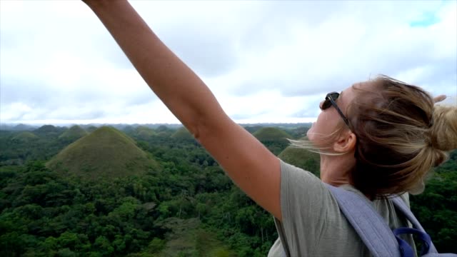 SLOW-MOTION-Woman-traveling-arms-outstretched-at-Chocolate-Hills-of-Bohol,-Philippines