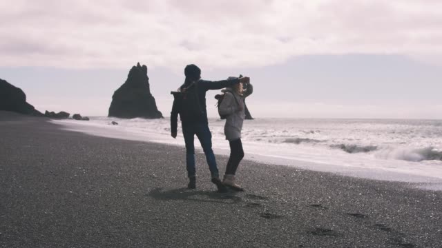 Junges-paar-liefen-schwarzen-Sandstrand-in-Island-und-etwas-Spaß,-Slow-motion