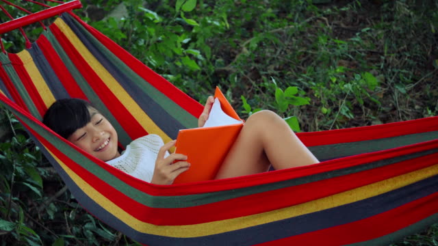 Kleines-Mädchen-auf-der-Hängematte-zu-entspannen-und-lesen-eine-Buch-Geschichte