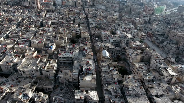 Aerial-view-of-ruined-homs-in-Syria,-birds-flying-in-the-sky