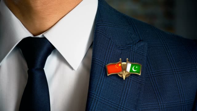 Empresario-caminando-hacia-cámara-con-amigo-país-banderas-Pin-China---Pakistán