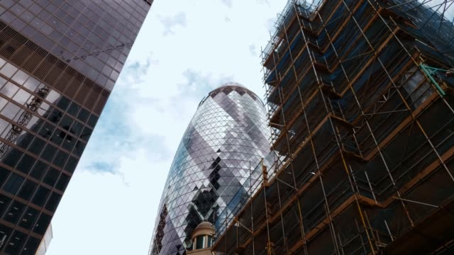 Nueva-construcción-y-edificio-Gherkin-Londres-con-nubes-y-reflejos-de-sol-4k