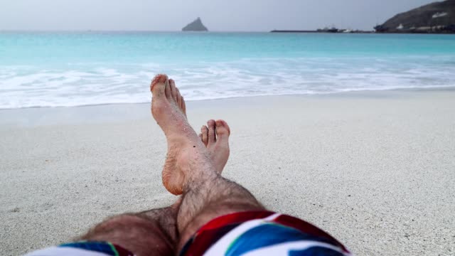 Mans-feet-on-sandy-beach.-Vacation-and-relaxation-concept,-beach-holidays-background.-4k-video