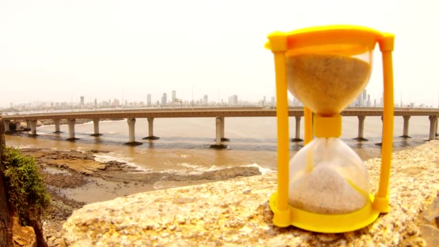 Bandra-Worli-Sea-Link-Mumbai-in-front-small-sandglass-sand-quickly-fall-hand-turns-it