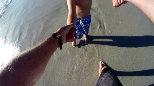 Cámara-lenta-punto-de-vista-del-padre-balanceo-niño-feliz-en-la-playa.