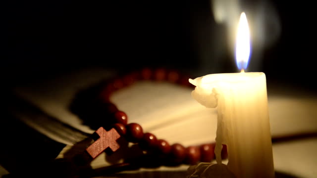 Kerzen-brennen-auf-dem-Hintergrund-der-heilige-Buch-und-einem-cross