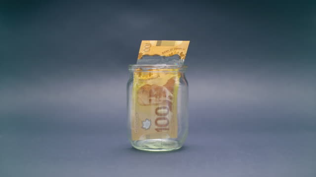 Frau-legt-kanadischer-Dollar-100-in-einem-Glas