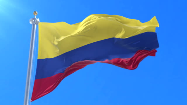 Colombia-flag-waving-at-wind-in-slow-with-blue-sky,-loop