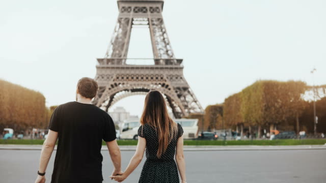 Junge-glückliche-Paar-zu-Fuß-nahe-des-Eiffelturms-in-Paris,-Frankreich.-Mann-und-Frau-umarmen-und-küssen-auf-der-Straße