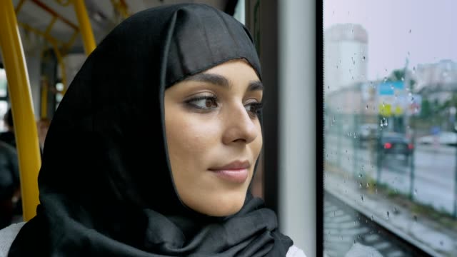 Joven-musulmana-de-dulce-en-hijab-es-ver-en-ventana-lluviosa-en-autobús,-concepto-de-transporte,-concepto-urbano,-concepto-de-tiempo,-soñando-con-concepto