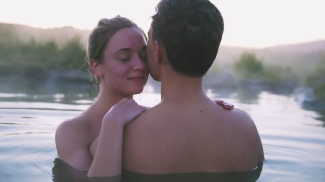 Happy-couple-in-love-bathing-and-relaxing-in-hot-pool-in-wild-landscape