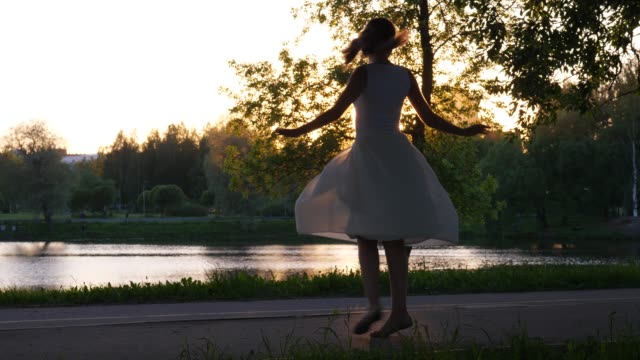 Girl-spin-around-in-airy-dress-against-setting-sun.