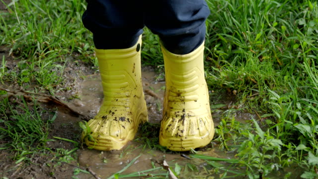 Little-child-in-bright-yellow-rubber-boots-splashing-in-a-puddle.-Kid's-feet-protected-from-dirty-water