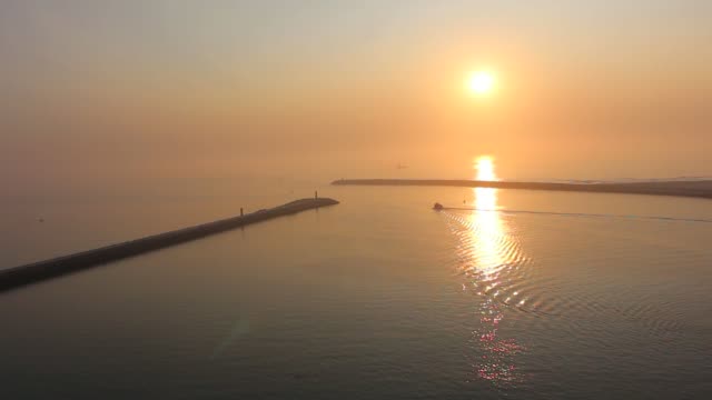 Einsames-Boot-langsam-verlassen-den-Hafen-und-Segeln-in-den-Sonnenuntergang-im-friedlichen-Ozean.