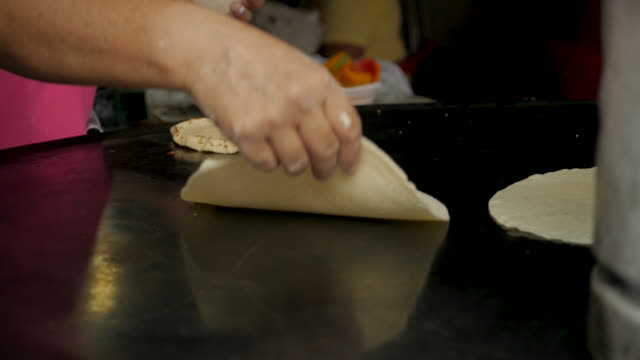Close-up-of-a-woman's-hand-flipping-a-handmade-corn-tortilla-on-a-metal-pan
