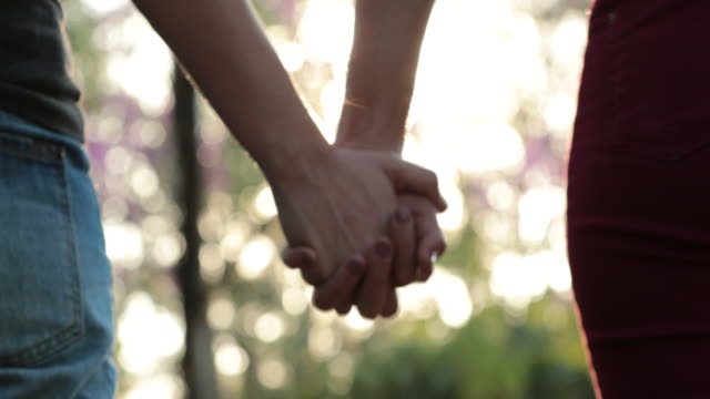 Joining-hands-together-at-the-park-with-sunlight-flare-in-the-background.-Concept-of-love,-affection,-friendship,-and-union