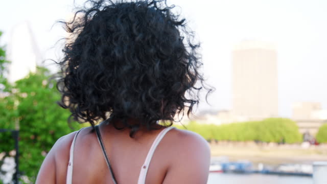Trendige-junge-schwarze-Frau-in-gestreiften-Hemd-und-Sonnenbrille-zu-Fuß-über-die-Brücke,-Rückblick-und-lächelnd-zu-Kamera,-folgen-Schuss