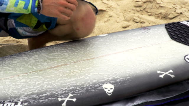 Applying-wax-on-a-surfboard