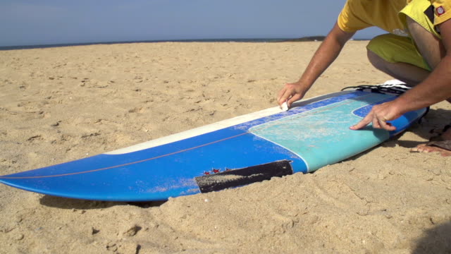 Surfer-waxing-his-surfboard