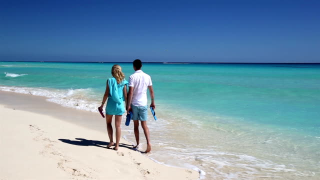 Young-couple-with-slippers-walking--along-the--beach
